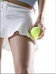 Mid section view of a young woman holding a tennis ball