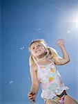 Low angle view of a girl smiling and surrounded by bubbles