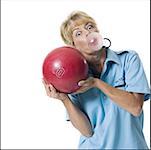 a female bowler playfully blows a bubble while holding up a ball