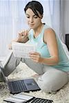 Mid adult woman sitting in front of a laptop looking at bills