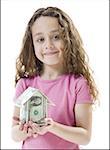 Portrait of a girl holding a house of paper money