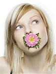 Nahaufnahme einer jungen Frau hält eine Blume in den Mund