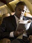 A businessman reading a newspaper in an airplane