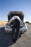 Rear view of a businessman looking at a car engine