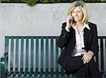 Businesswoman sitting on a bench and talking on a mobile phone