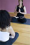 Rear view of an adult woman practicing yoga with a young woman