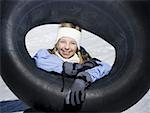 Portrait of a girl sitting on the snow with an inner tube