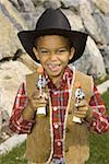 Bildnis eines Knaben in einem Cowboy-Kostüm hält eine Spielzeug-Pistole