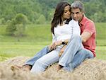 man and a woman sitting on a hay bale