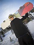 Young man holding a snowboard on his shoulders