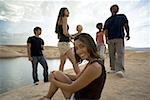 Portrait d'une jeune femme assise sur un rocher avec des amis en arrière-plan