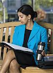 Geschäftsfrau, die auf einer Bank sitzen und Lesen von Dokumenten in einer Kaffeepause