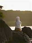 Rear view of a woman sitting on a rock