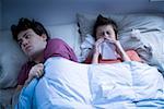 Homme pose dans son lit avec une femme être mouché avec tissu