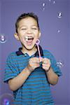 Close-up of a boy blowing bubbles with a bubble wand