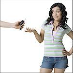 Close-up of a person's hand offering car keys to a teenage girl