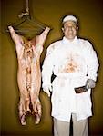 Butcher with hanging carcass and knife smiling