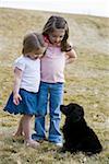 Two girls hugging with puppy outdoors