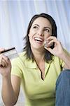 Gros plan d'une femme adulte mid parler sur un téléphone mobile tenant une carte de crédit