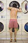 Man in boxers looking in dryer at Laundromat