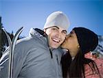 Close-up of a young woman kissing a young man on the cheek