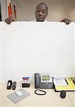 Businessman peeking over cubicle wall