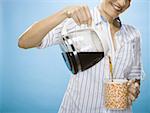 Close-up of a young woman pouring coffee into a mug
