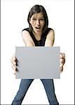 Portrait of a young woman holding a blank sign