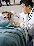 Male doctor talking to young girl in hospital bed