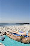 Profile of two young women sunbathing on the beach