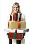 Jeune femme tenant une pile de cadeaux