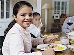 Portrait d'une jeune adolescente, assis à une table à manger et souriant