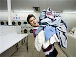 Man with pile of clothing in Laundromat