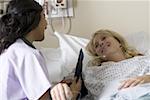 A female patient wearing blood pressure gauge and smiling at a female doctor