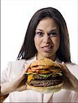 Portrait d'une jeune femme tenant un hamburger et faire un visage