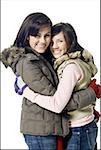 Two women hugging and smiling with winter coats