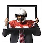 Businessman holding picture of football player with helmet