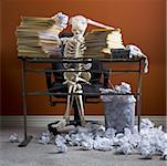 Squelette assis au comptoir avec des piles de papiers et de papiers froissés