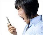 Profile of a mid adult woman shouting and holding a flip phone