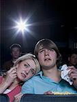 Boy and girl with tissues crying at movie theater