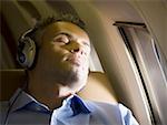 Gros plan d'un homme d'affaires de sommeil et écouter de la musique sur le casque dans un avion