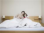 Male mannequin and a female mannequin reclining on the bed and laughing
