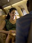 A businesswoman looking at a businessman and smiling on an airplane