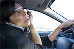 Nahaufnahme von einer Frau mittleren Alters auf einem Handy sprechen und Anwenden von Eyeliner während der Fahrt