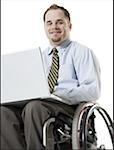 Portrait of a young man sitting in a wheelchair using a laptop