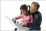 Girl sitting on her father's lap, using a laptop