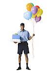 Young man carrying gift boxes while holding balloons