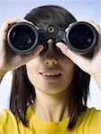 Close-up of a young woman looking through a pair of binoculars