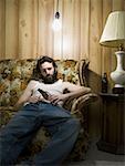 Man sitting on sofa with cigarette and beer bottle