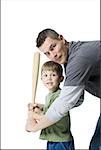 Portrait of a father teaching his son how to swing a baseball bat